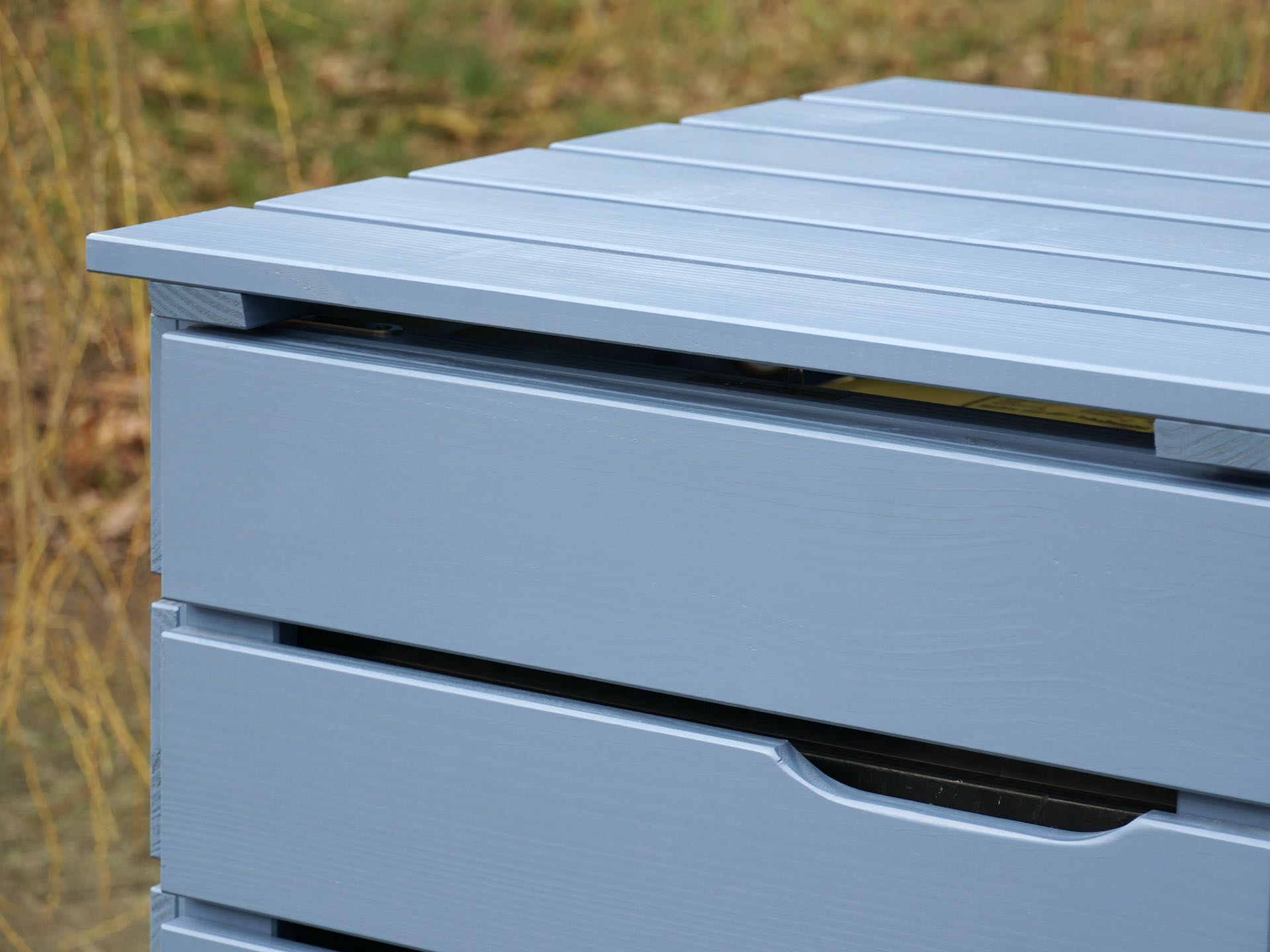 Detailaufnahme des linken Deckels und Tür-Ausschnitts der Mülltonnenbox in Taubenblau