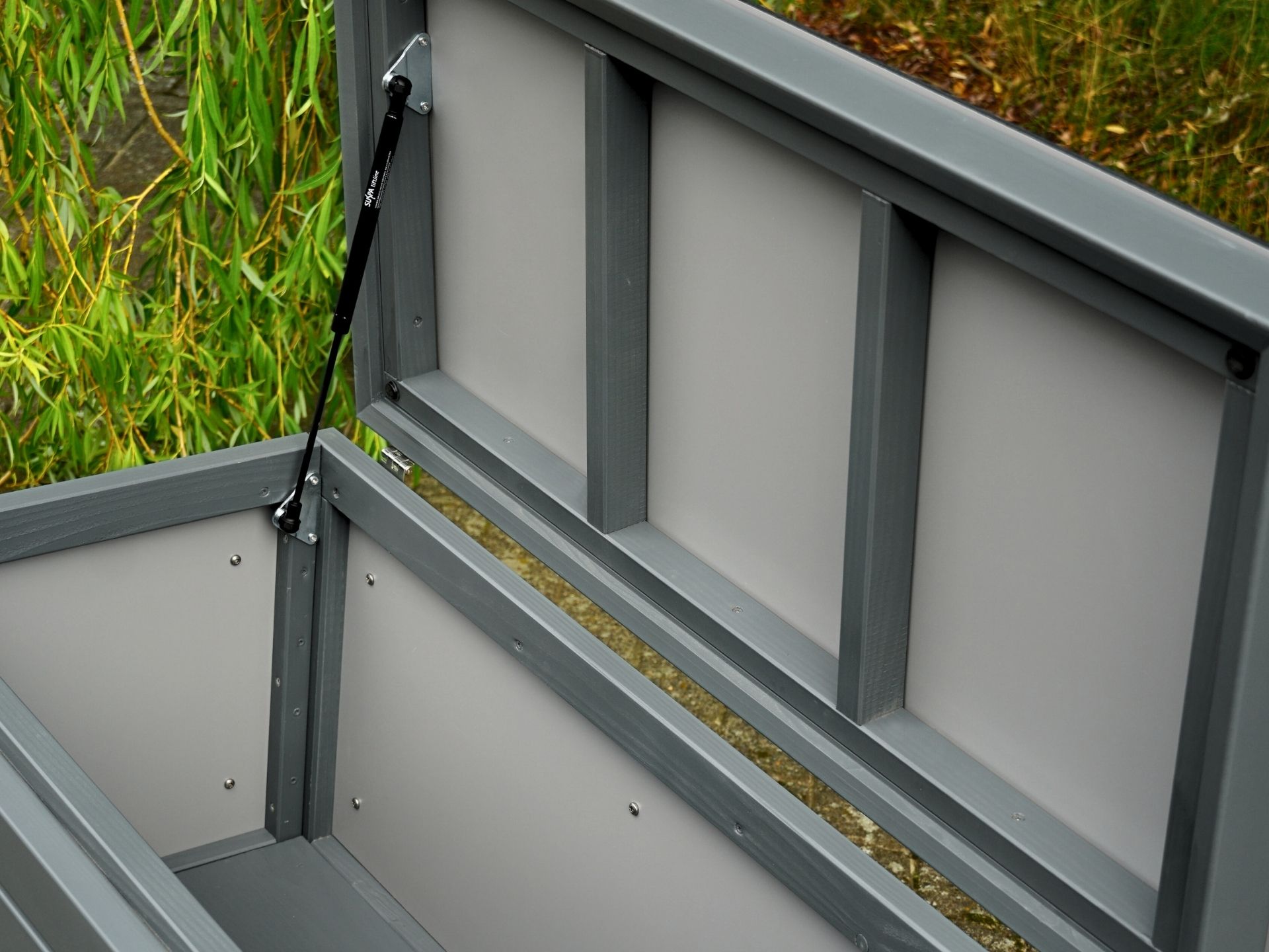 Innenansicht der Gartenbox Rhombus in Basaltgrau – von vorn links fotografiert, mit kontrastierendem Boden in Basaltgrau und HPL-Innenverkleidung