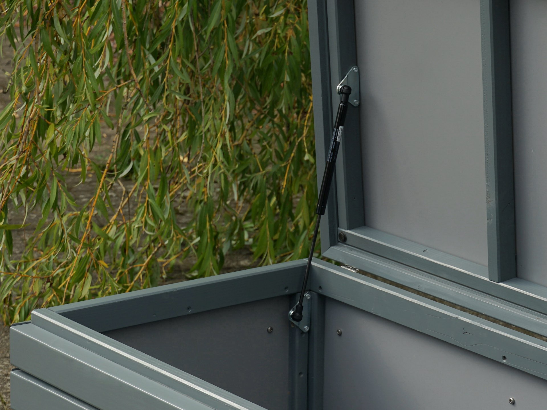 Innenansicht des geöffneten Deckels der Gartenbox in Grau – Gasdruckfeder und HPL-Innenverkleidung sichtbar	