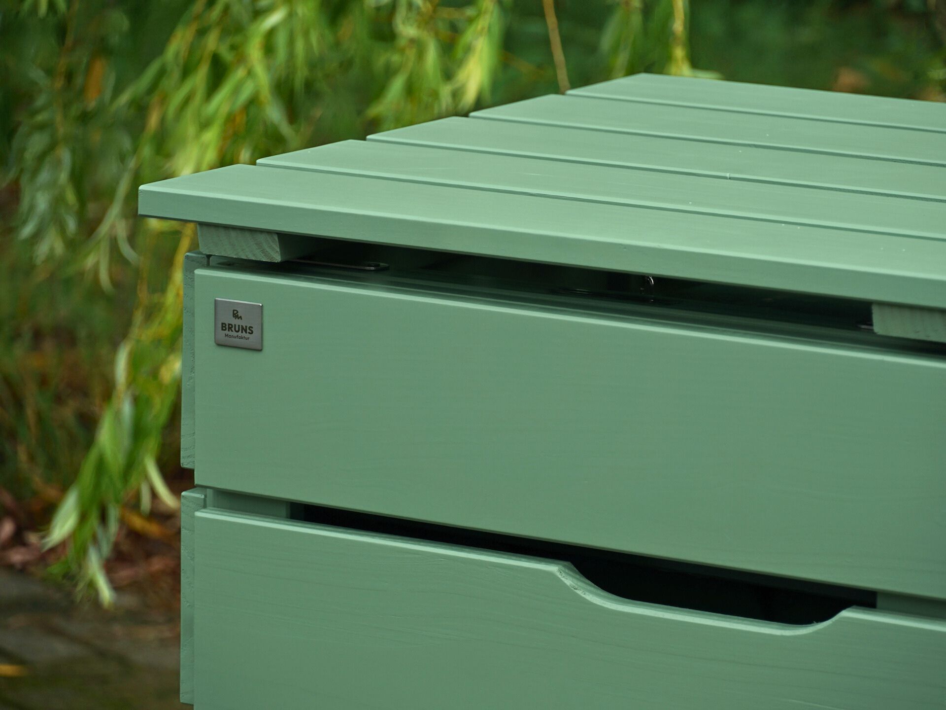 Detailaufnahme des linken Deckels und Tür-Ausschnitts der Mülltonnenbox in Blassgrün