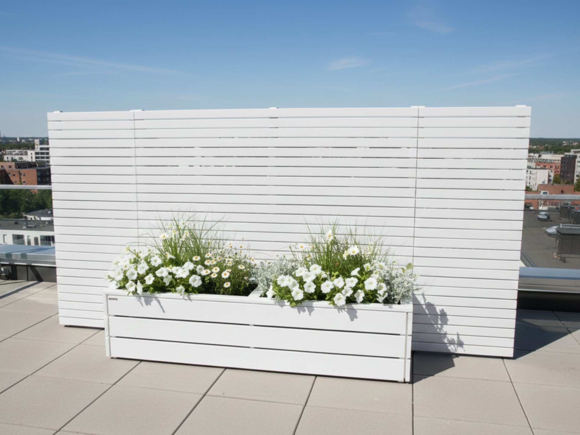 Langer weißer Pflanzkasten mit Sichtschutz und seitlichen Verlängerungen auf einer Dachterrasse, ideal für Privatsphäre und Begrünung.
