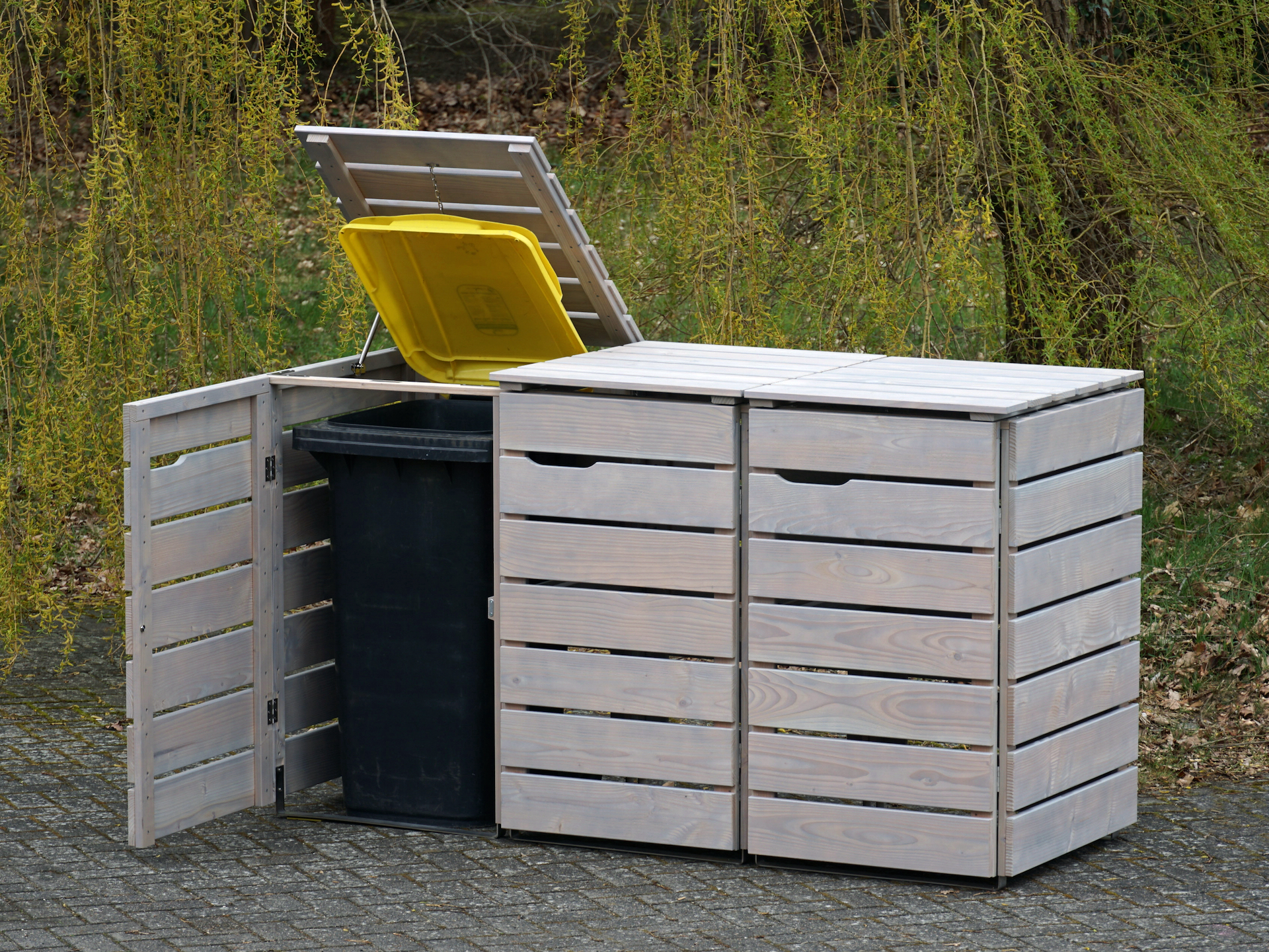 Holzbox für drei Tonnen – mit einfacher Deckelöffnung für schnelle Nutzung 3er Mülltonnenbox in Grau Geölt, von vorn rechts, linker Deckel und Tür geöffnet
