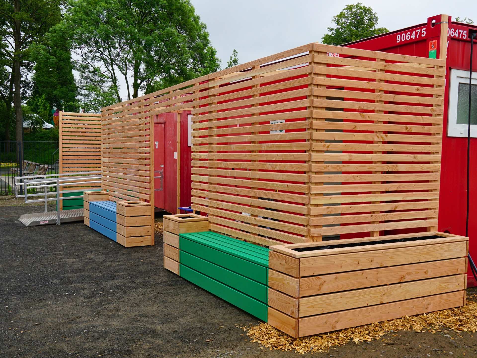 Sichtschutz-Anlage mit Sitzbänken und Pflanzkästen zur funktionalen Verkleidung von WC-Containern – Gesamtansicht