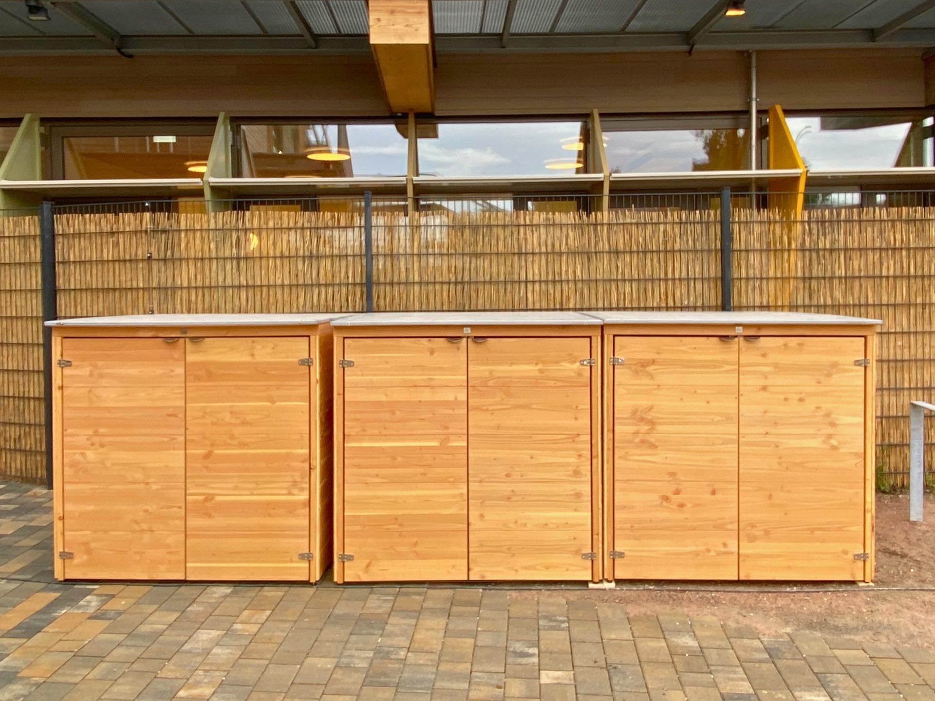 Drei Kinderwagenboxen Cubus aus geöltem Holz mit Edelstahldach für Kitas und Einrichtungen.