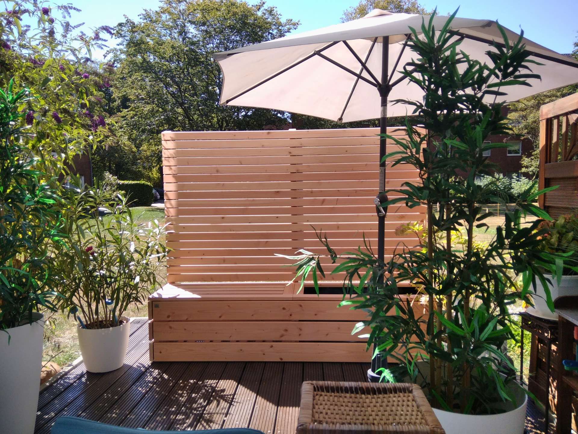 Freistehender Sichtschutz aus Holz mit Pflanzkasten und integrierter Sitzbank, fertig montiert geliefert.