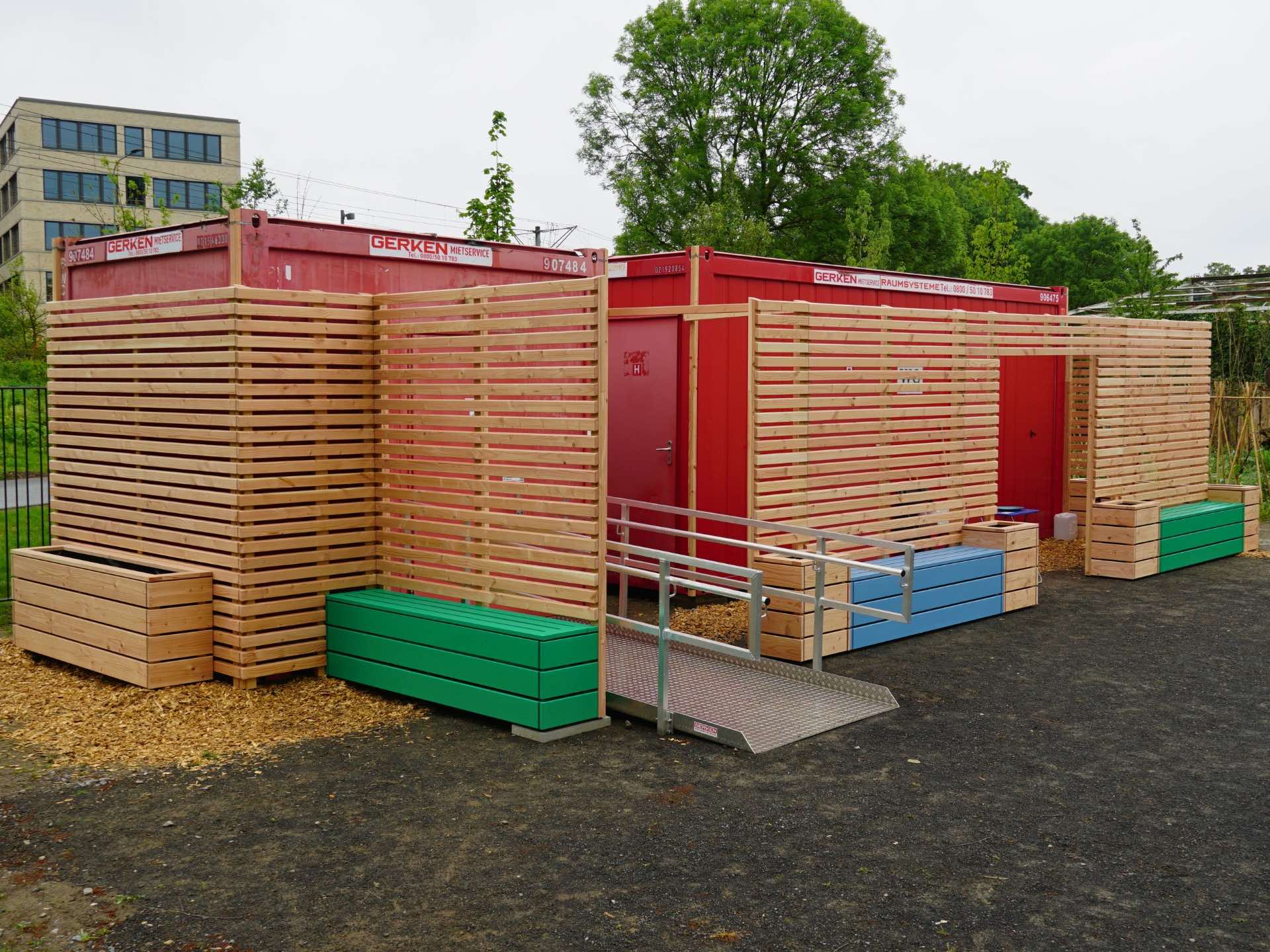Sichtschutz-Anlage mit Wandverkleidung aus Rhombusprofilen zur Kaschierung von WC-Containern – Ansicht von links