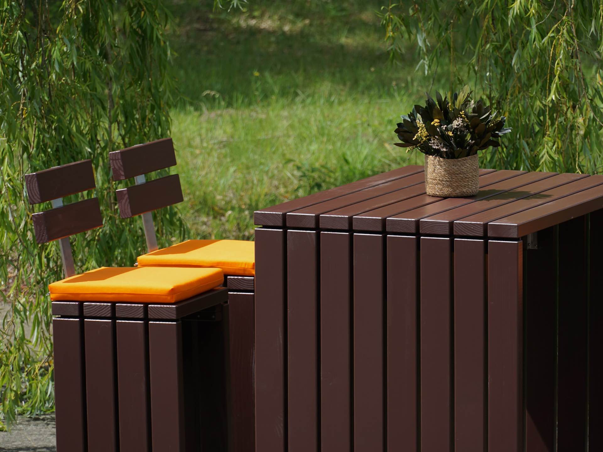 Detailaufnahme des Kubus Stehtischs, Douglasienholz dunkelbraun, mit zwei teilweise sichtbaren Hockern