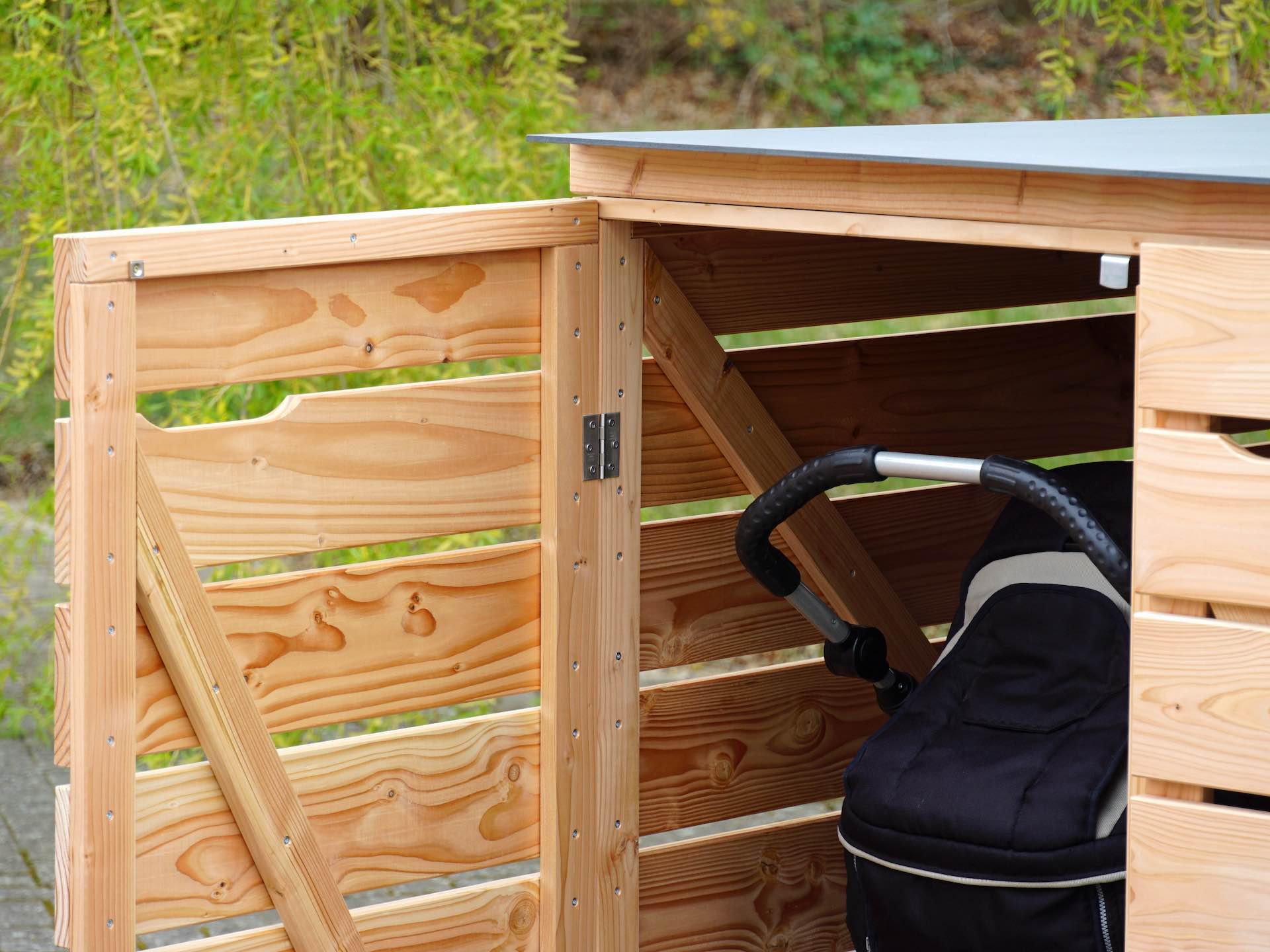 Blick durch die geöffnete linke Tür der Kinderwagenbox, innen ein Kinderwagen sichtbar