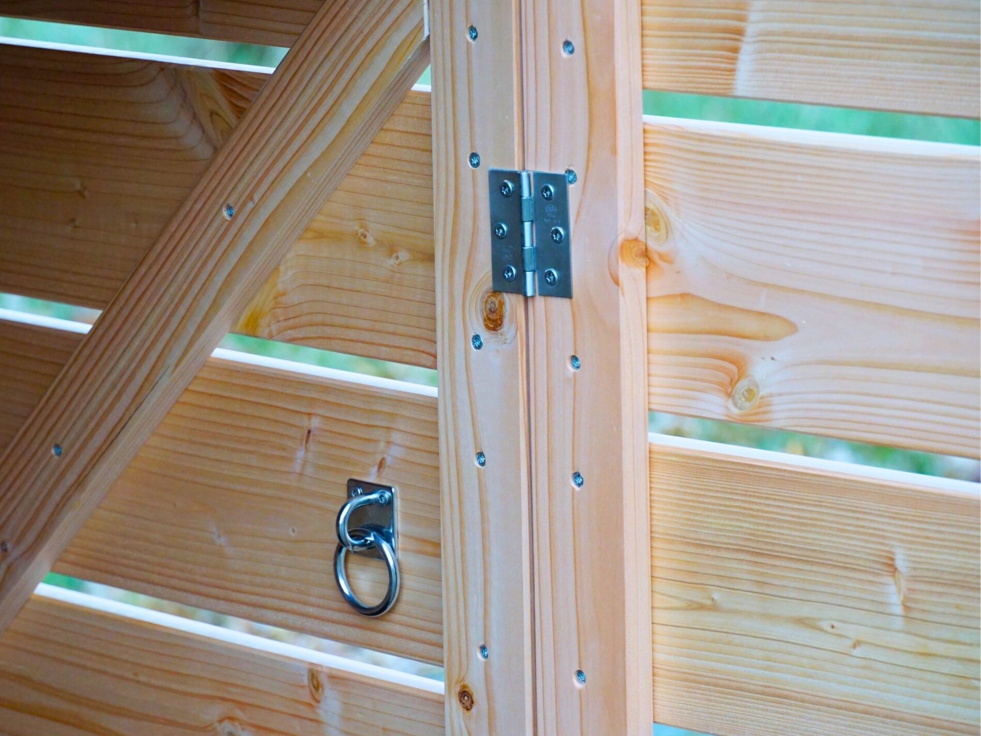 Detailaufnahme des witterungsbeständigen Douglasienholzes, Edelstahl-Scharnier, Schrauben und Schloss-Öse zum Sichern von Kinderwagen mit Fahrradschloss