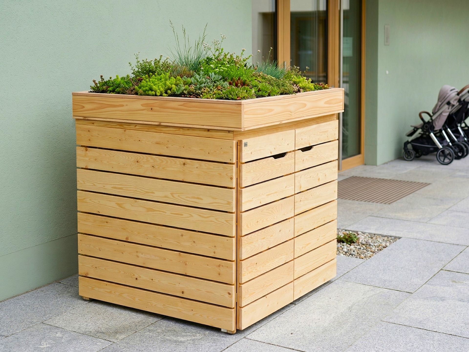 Kinderwagenbox aus Douglasie mit bepflanztem Gründach als funktionale und begrünte Lösung im Außenbereich.