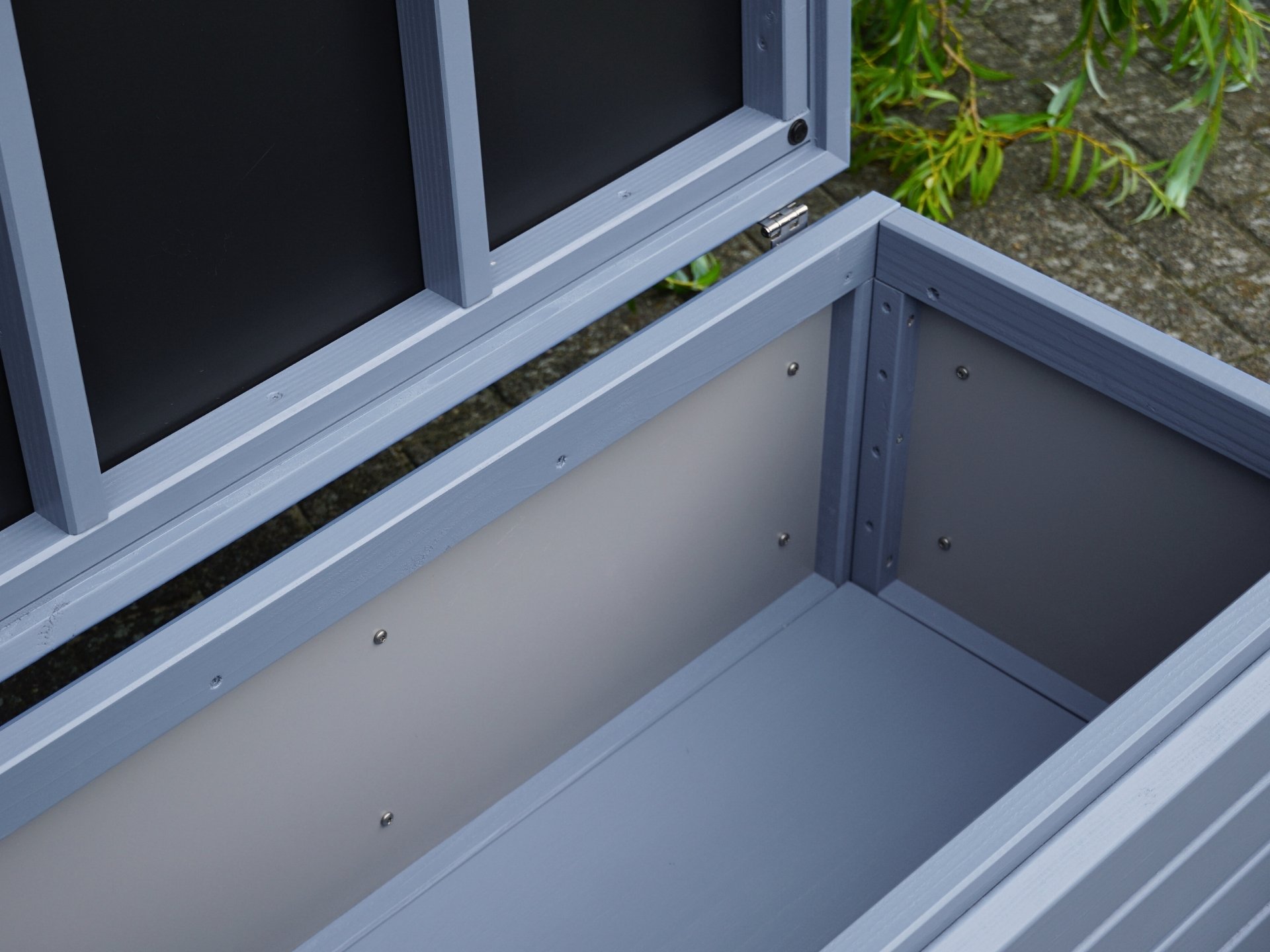 Innenansicht der Gartenbox Rhombus in Taubenblau – von vorn links fotografiert, mit taubenblauem Boden und Innenverkleidung aus HPL