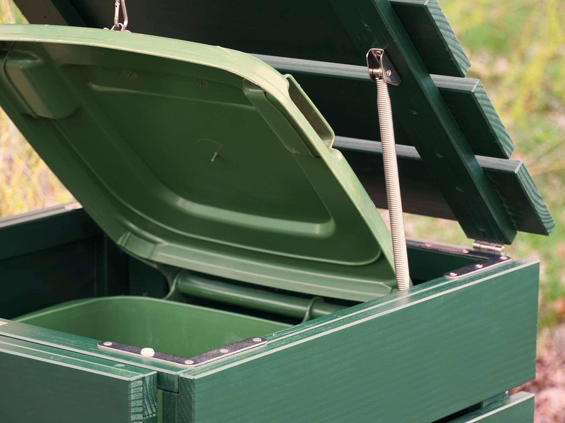 Detailaufnahme des geöffneten Deckels mit Edelstahl-Feder an der moosgrünen Mülltonnenbox