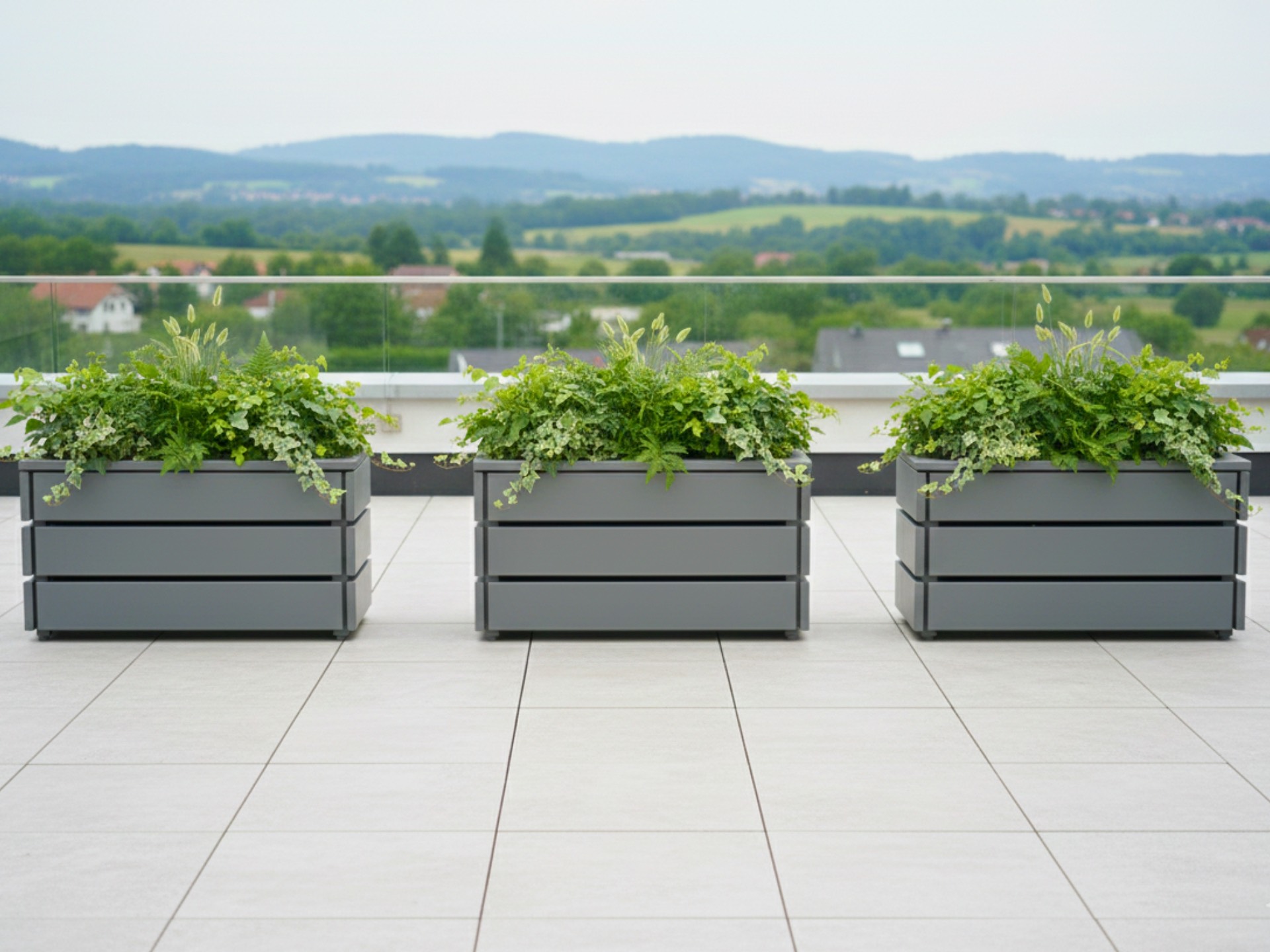 Drei Pflanzkästen Classic M in Basaltgrau auf einer Dachterrasse, kompakte Begrünung mit moderner Optik.