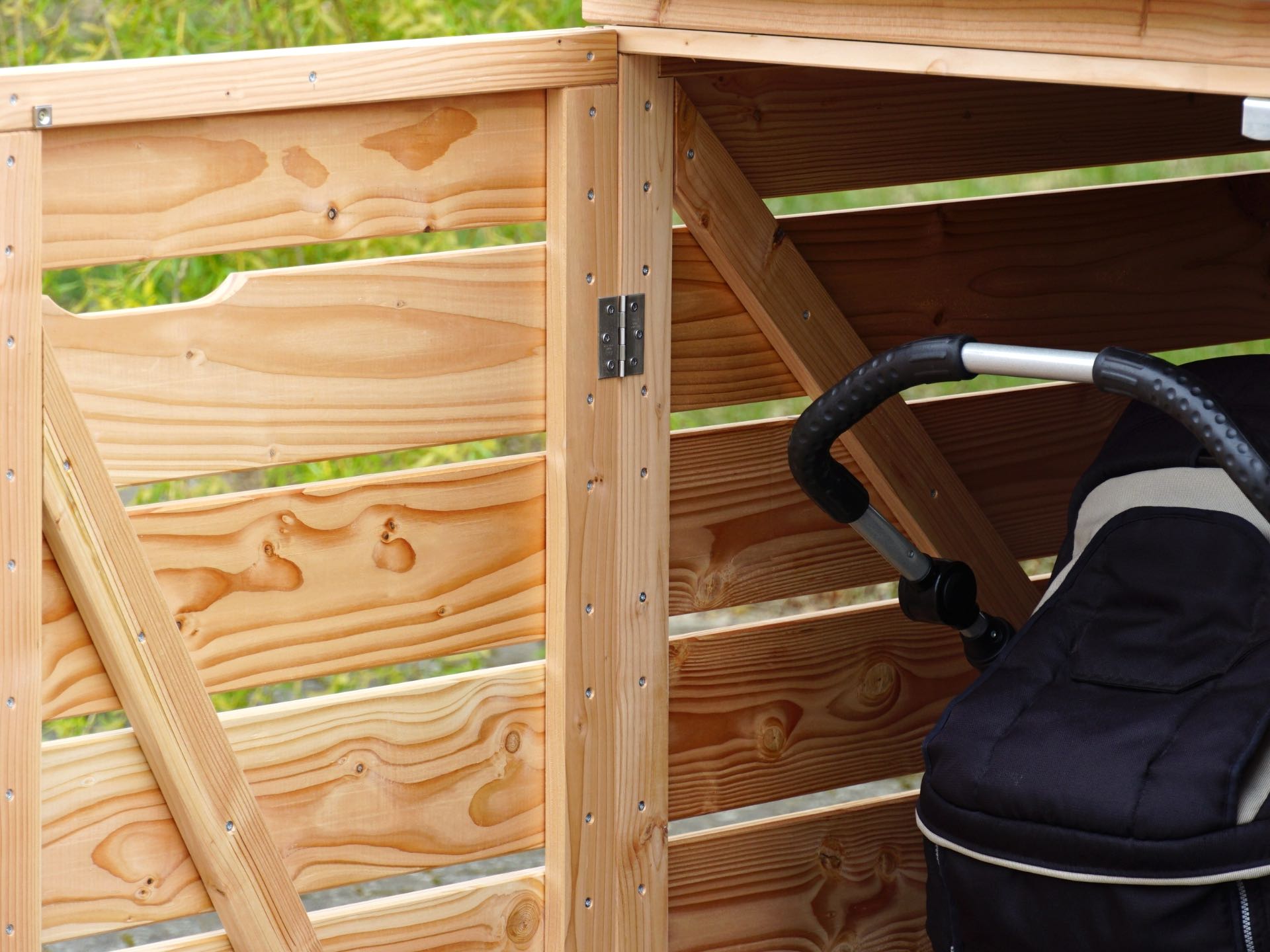 Kinderwagenbox mit Gründach in Natur Geölt – wetterfeste Douglasie und Edelstahl-Scharniere – Detail	Kinderwagenbox – Natur Geölt – Edelstahl Scharniere – Detail 2	Innenansicht mit Fokus auf Stauraum	