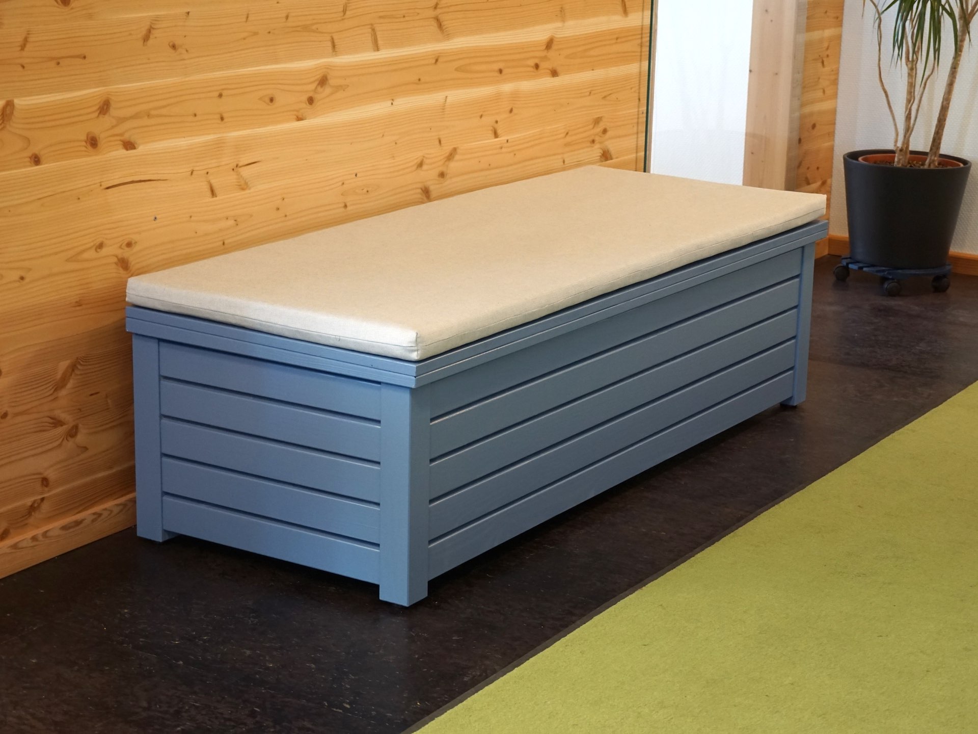 Gartenbox in Taubenblau mit Massivholzdeckel und hellgrauem Polster – Gesamtansicht von vorn links	