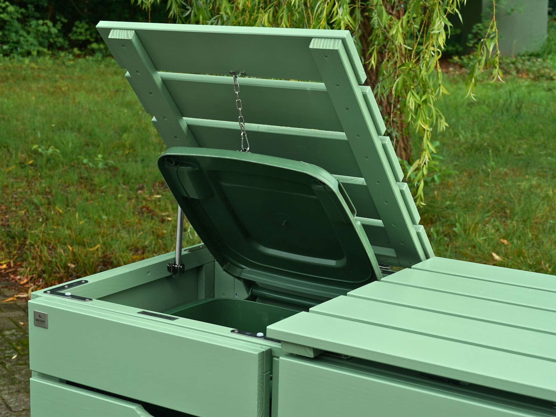 Detailaufnahme des geöffneten linken Deckels der Mülltonnenbox in Blassgrün mit Edelstahl-Feder