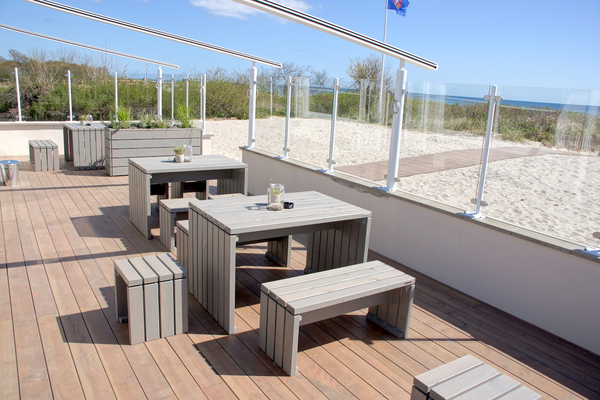 Terrasse des Cafés Strandliebe in Retin, eingerichtet mit maßgefertigten Gartenmöbeln und hohen Pflanzkästen in Grau Geölt von BRUNS Manufaktur