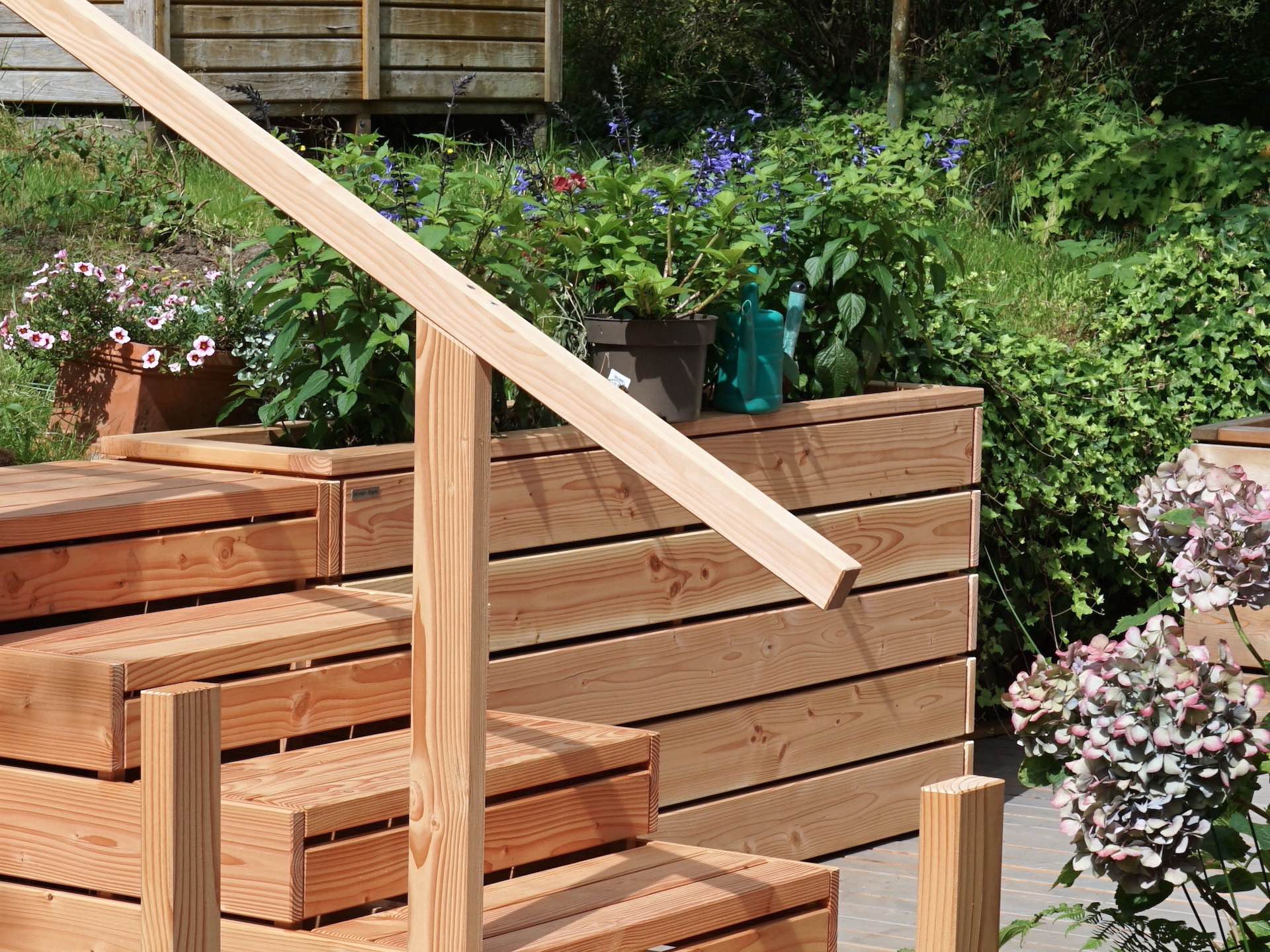 Detailaufnahme von links - Treppe mit Treppengeländer, ein bepflanzter Pflanzkasten im Hintergrund