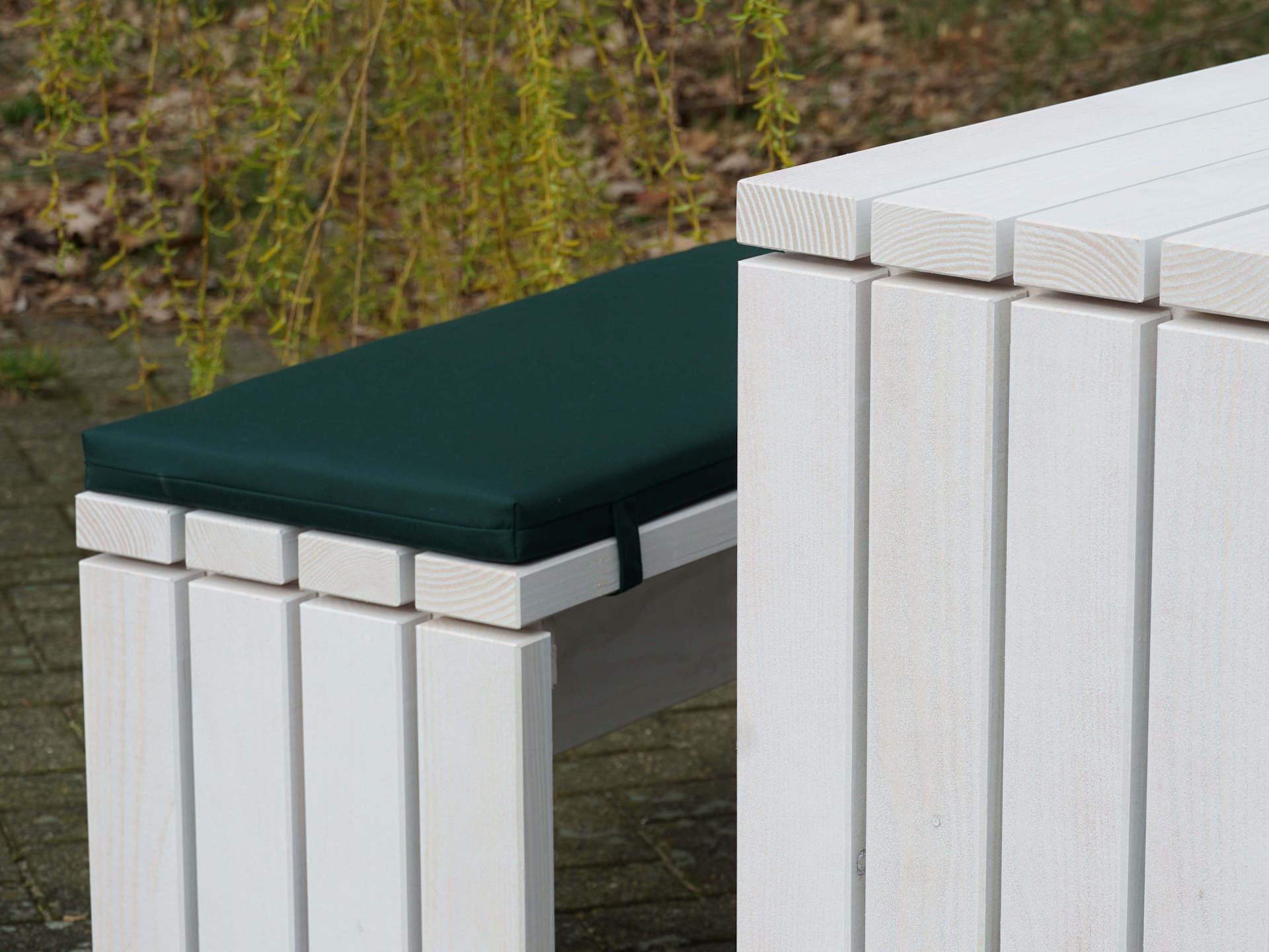 Detailaufnahme von Tisch und Bank des Gartenmöbel-Sets Kubus, weiß geöltes Douglasienholz, grüne Polsterung