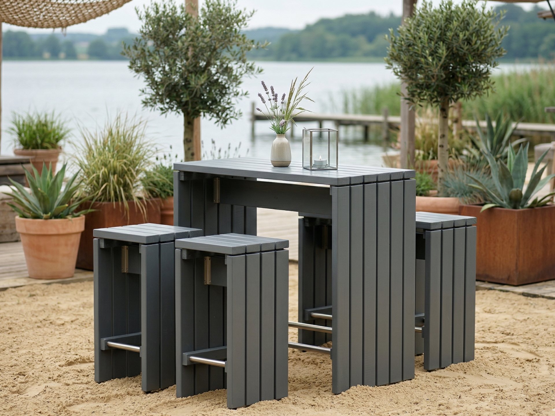 Bartisch Set in grauem Holz mit hohem Tisch und vier Hockern auf Terrasse am Seeufer.