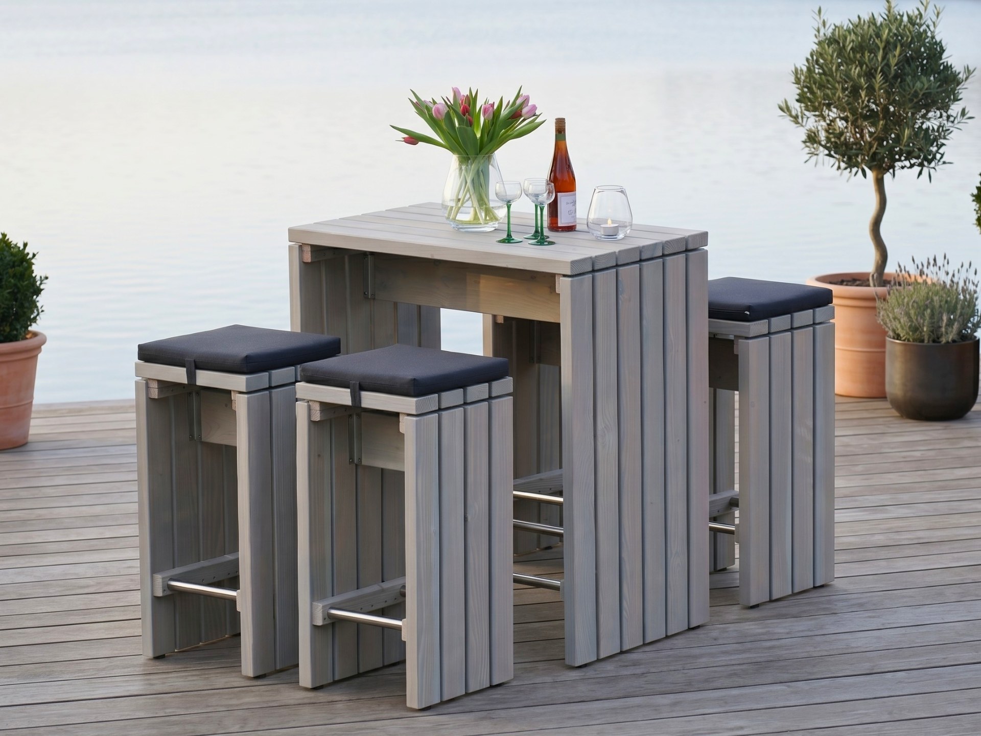 Barmöbel Set in Grau Geölt mit Stehtisch und vier gepolsterten Barhockern auf Terrasse am See.