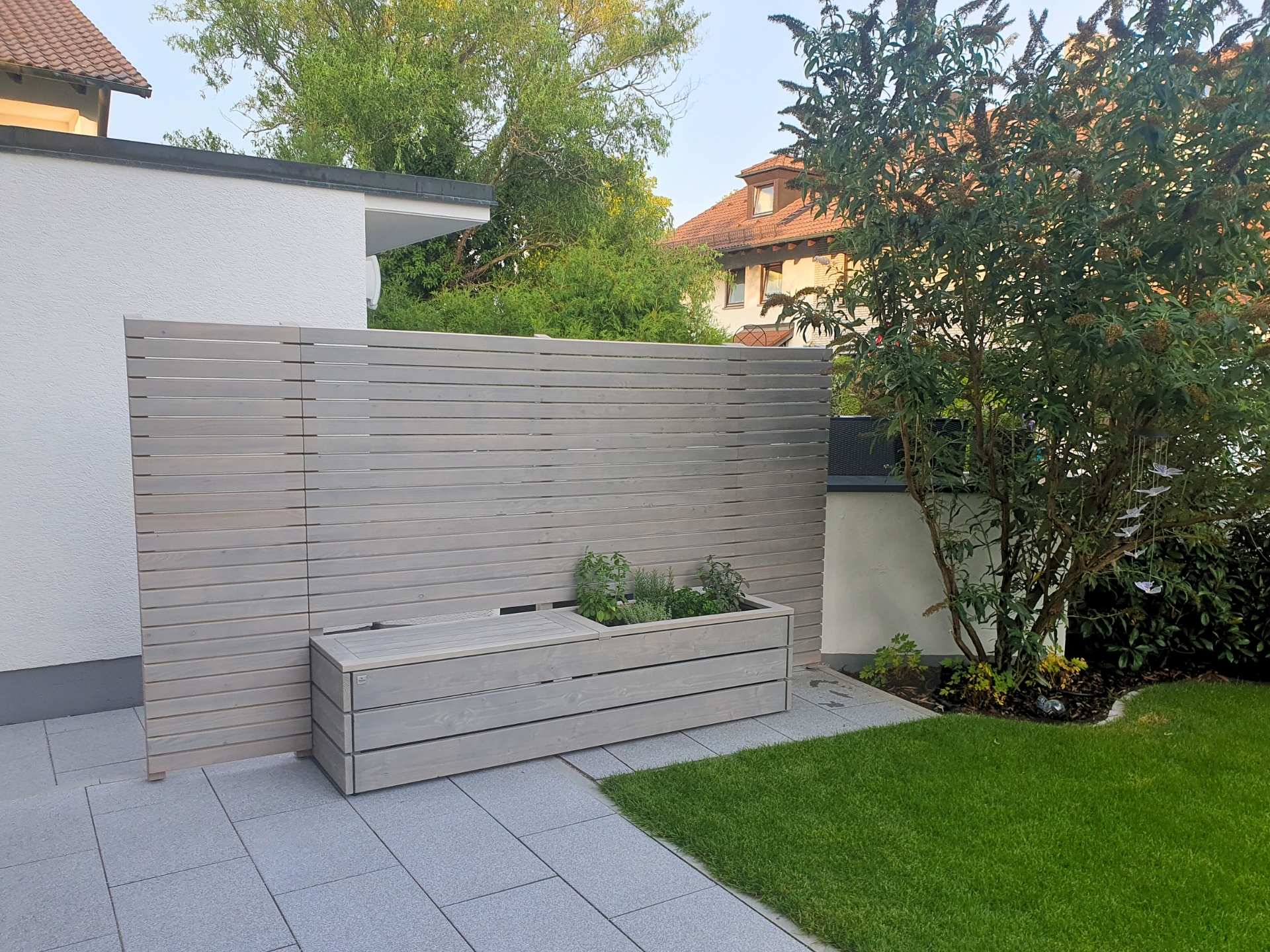 Sichtschutz mit Pflanzkasten & Bank Grau geölt – Terrasse & Garten Sichtschutz mit Pflanzkasten und Bank aus grau geöltem Holz, mit seitlicher Verlängerung. Weiterer Blick auf Terrasse und Umgebung, wetterfest & nachhaltig.