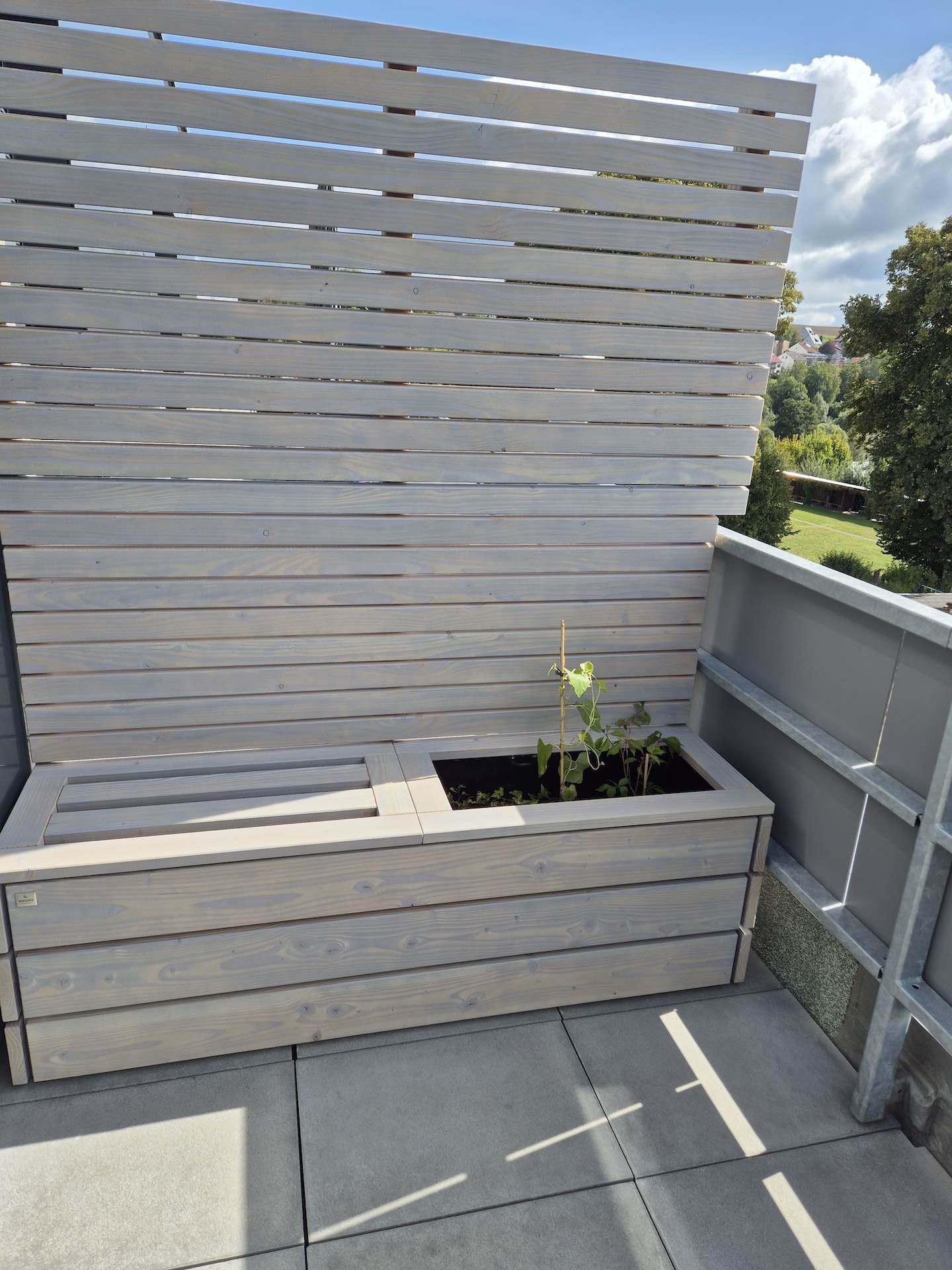 Sitzbank mit Pflanzkasten und Sichtschutzwand in Grau geölt – idealer Balkon- oder Terrassentrenner für mehr Privatsphäre.
